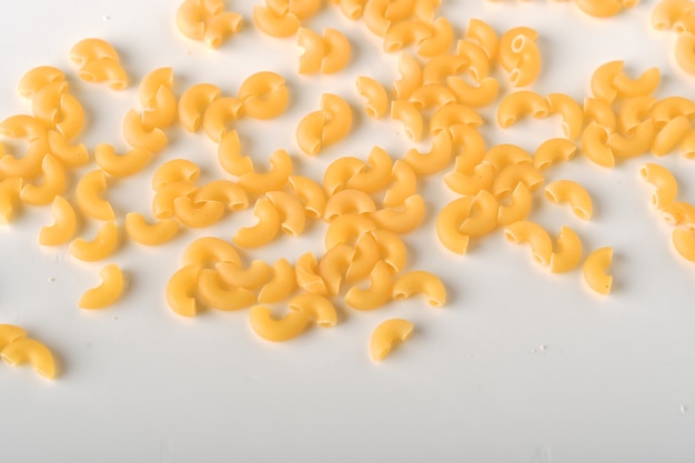 uncooked elbow macaroni on a white background