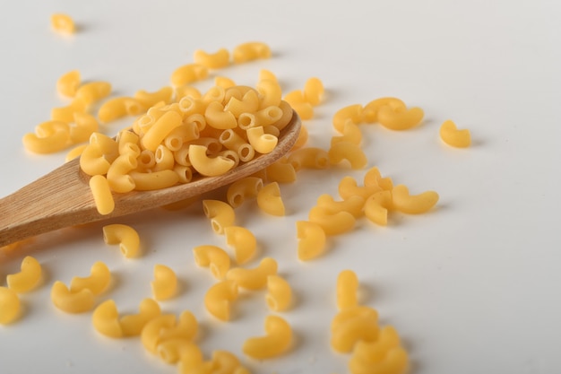 uncooked elbow macaroni on a white background