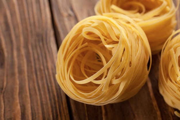 Uncooked fettuccine pasta ball, on textured wooden background. set of several different foreshortenings