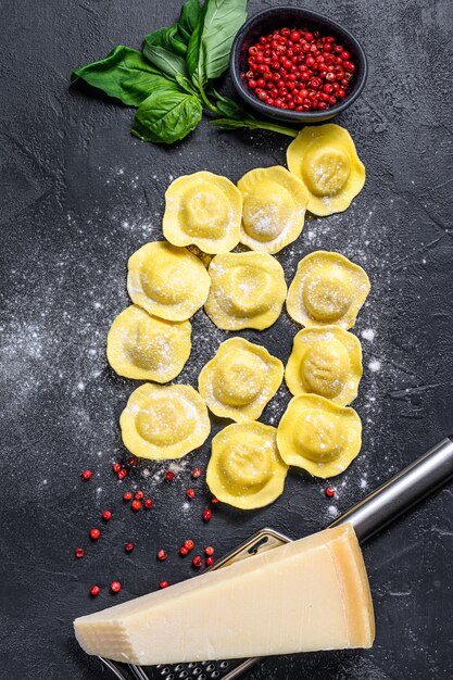 Uncooked fresh ravioli. Home Italian cuisine. Black background. Top view.