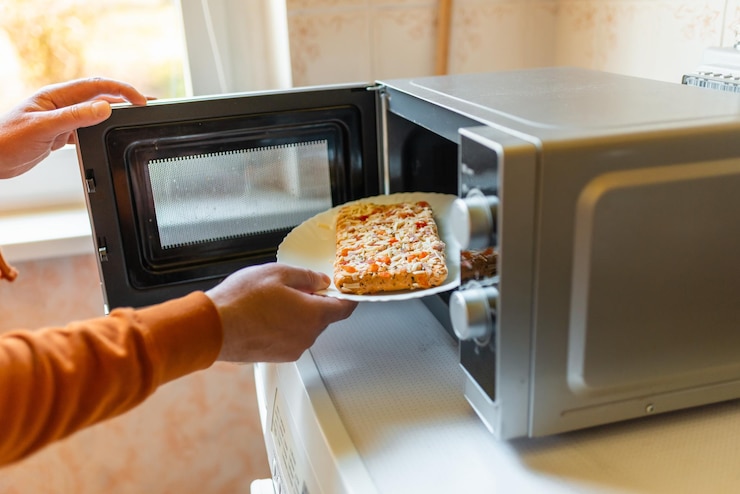 Photo uncooked frozen small pizza placed into the microwavejunk foodfast food conceptside viewselective focus