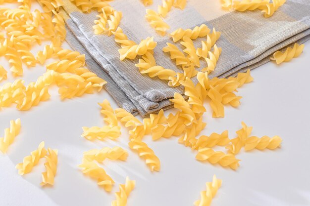 Photo uncooked fusilli pasta scattered on white table