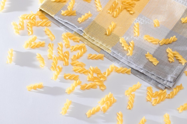 Uncooked fusilli pasta scattered on white table