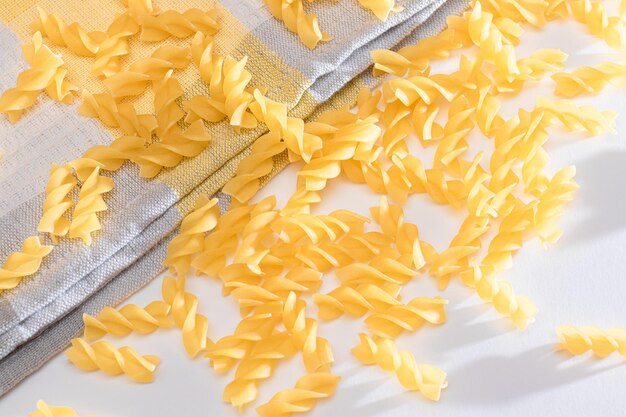 Uncooked fusilli pasta scattered on white table