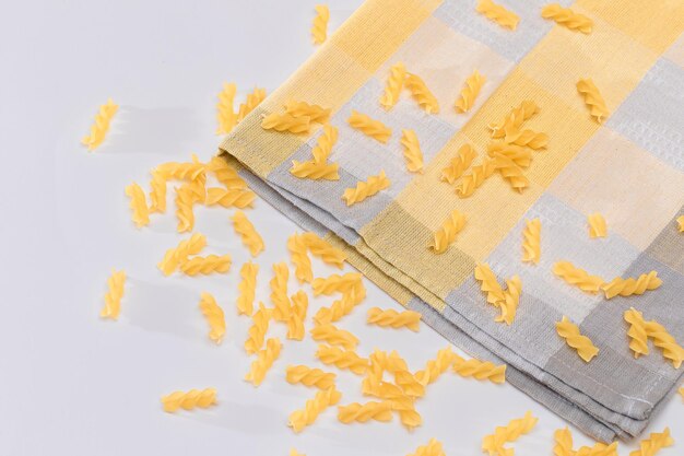 白いテーブルに散らばった未調理のフジッリ パスタ