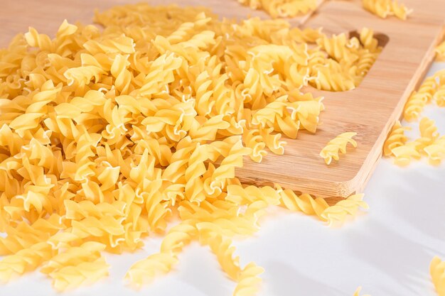 Uncooked fusilli pasta scattered on wooden board