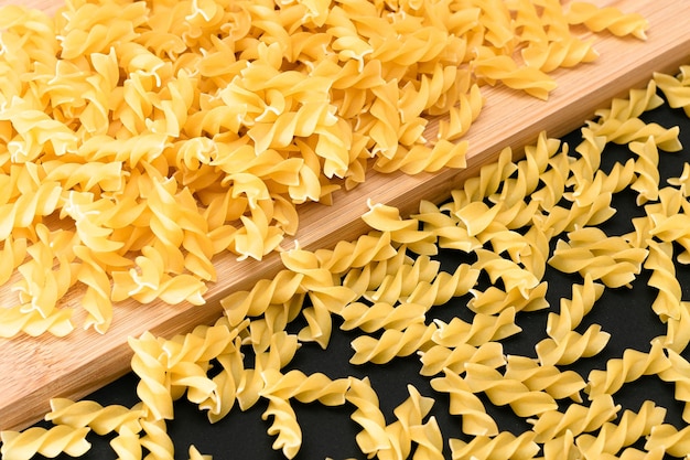 木の板に散らばった未調理のフジッリ パスタ