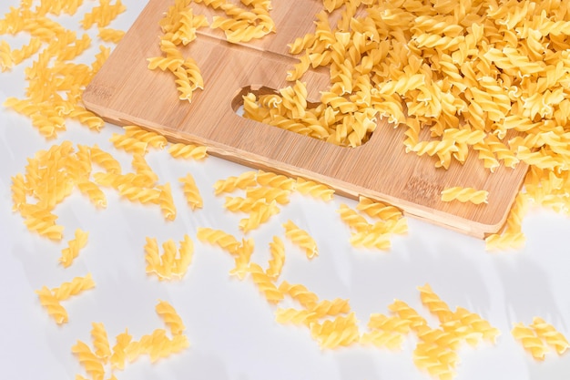 Foto fusilli crudi sparsi su tavola di legno