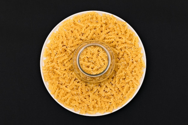 Uncooked fusilli pasta on white plate