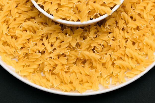 白い皿に未調理のフジッリパスタ