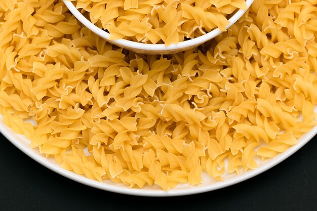 Uncooked fusilli pasta on white plate