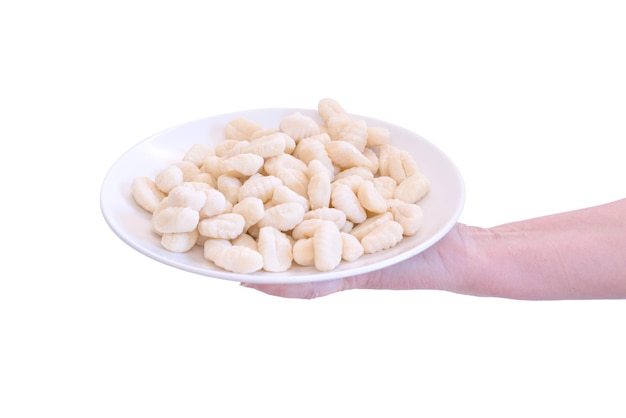 An uncooked Gnocchi lays on a white plate in a woman's hand isolated on a white background Rough Nutritious Prepare Preparation Eating Culinary Carbohydrates Gastronomy Gnocci Kitchen