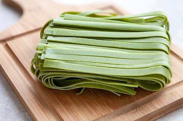 Uncooked green spinach homemade Italian tagliatelle pasta close up