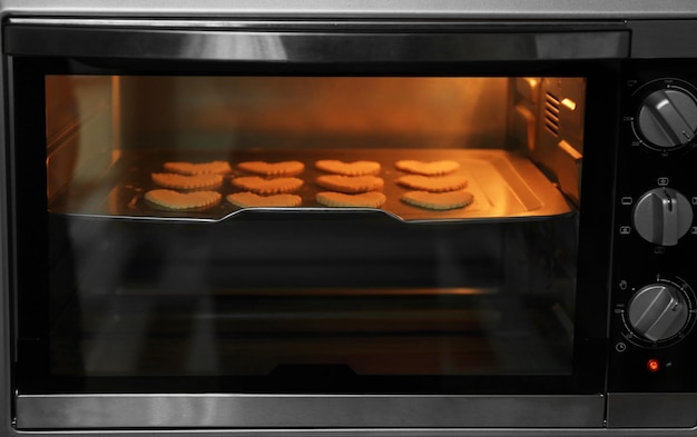 Uncooked heart shaped biscuits on a baking tray in an oven