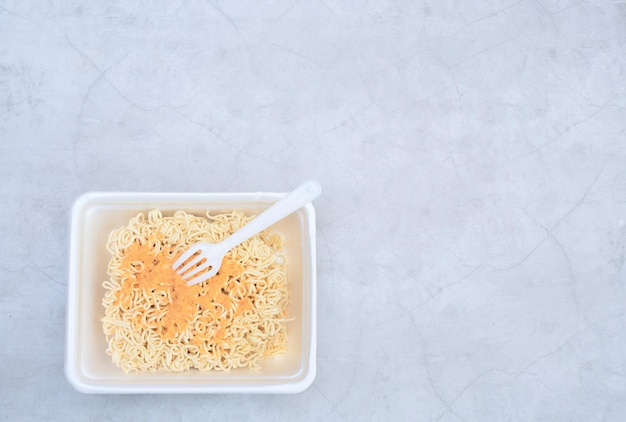 Uncooked instant Chinese curly noodles in takeout packaging with plastic fork Selective focus Asian food and delivery concept Unhealthy eating