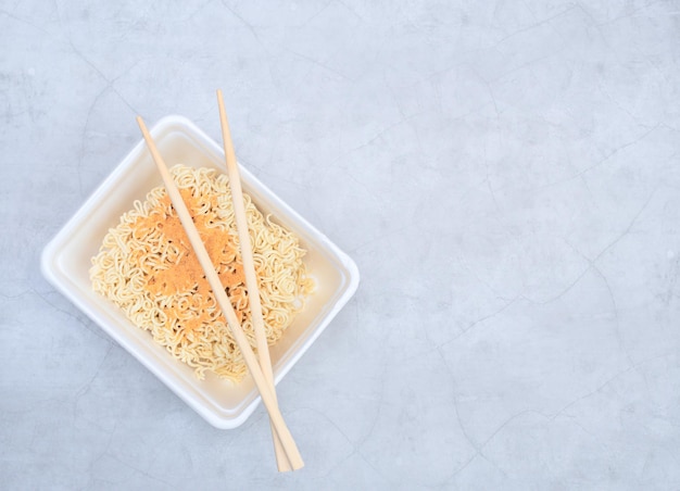 Uncooked instant Chinese curly noodles in takeout packaging with wood sticks Selective focus Asian food and delivery concept Unhealthy eating