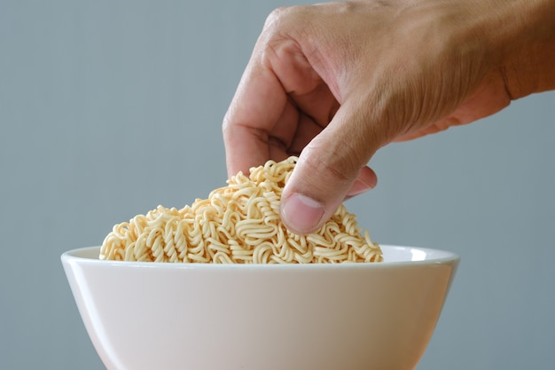 Photo uncooked instant noodles and white bowl on wooden table