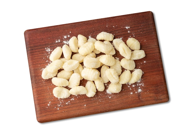 Foto gnocchi di pasta italiani crudi su una tavola di legno isolata sopra priorità bassa bianca.