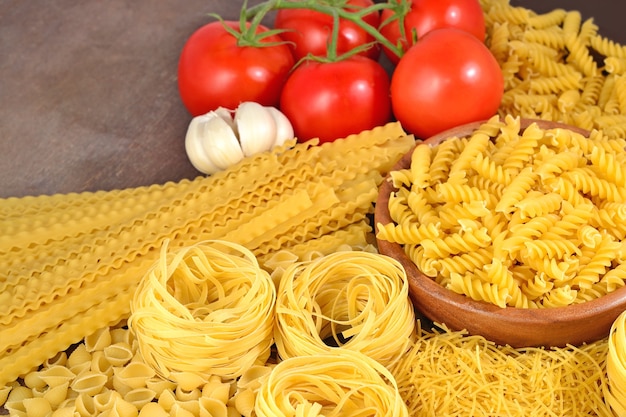 Pasta italiana cruda, ramo di pomodori maturi e aglio