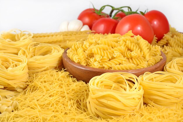 Uncooked Italian pasta and ripe tomatoes branch on a white background