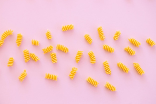 Uncooked italian spiral pasta on pink background