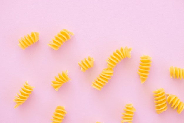 Uncooked italian spiral pasta on pink background