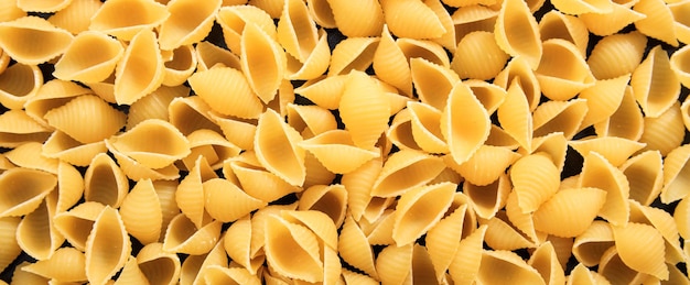 Uncooked macaroni shell shape pasta texture background banner