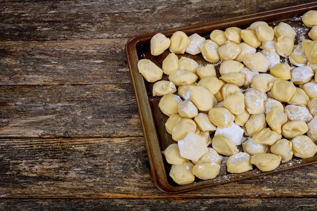 Uncooked meat dumplings ravioli pelmeni on old wooden table