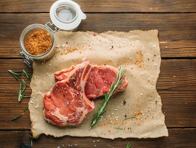 Uncooked meat in seasoning on wooden table