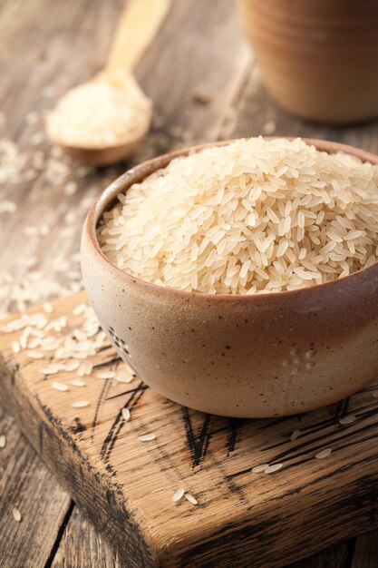 Uncooked parboiled rice in a bowl on wooden table