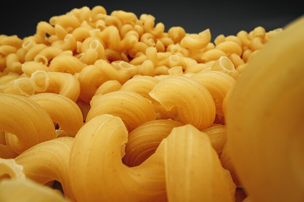 Uncooked pasta swirls on dark background macro photo