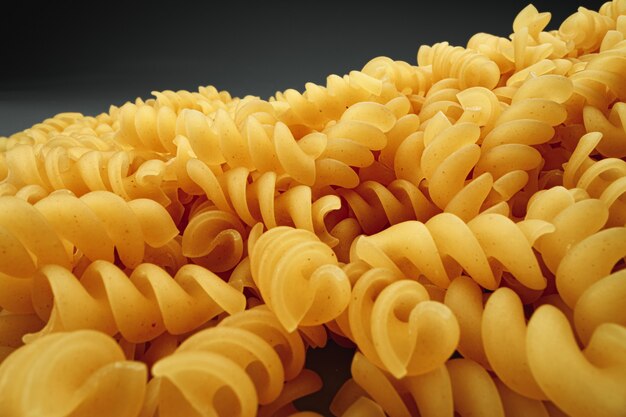 Uncooked pasta swirls on dark background macro