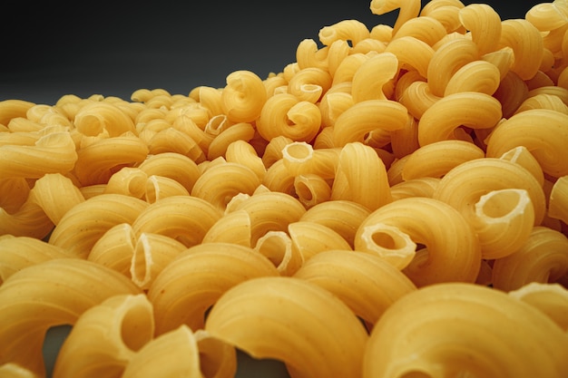 Uncooked pasta swirls on dark macro