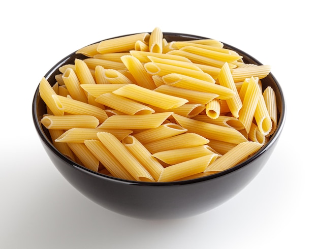 Uncooked penne pasta in black bowl isolated on white background with clipping path