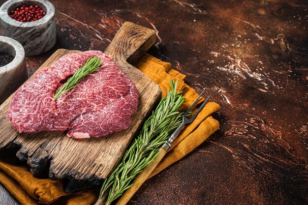 Uncooked Raw beef veal cheeks on wooden board Dark background Top view Copy space