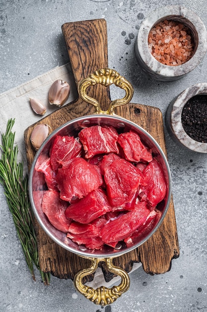 Uncooked Raw diced beef veal meat for stew in skillet. Gray background. Top view.