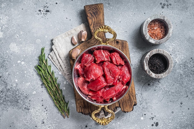 Uncooked Raw diced beef veal meat for stew in skillet Gray background Top view