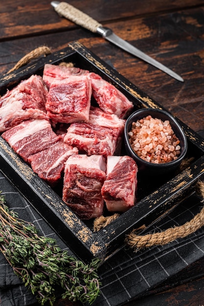 Uncooked Raw diced cubes of lamb meat in wooden tray with salt and thyme Wooden background Top view