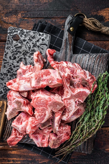 Photo uncooked raw meat diced for stew on a butcher board. dark wooden background. top view.