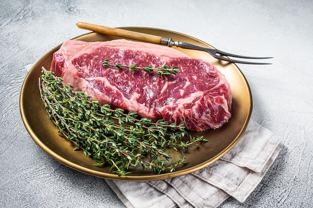 Uncooked Raw New York beef steak with thyme White background Top view