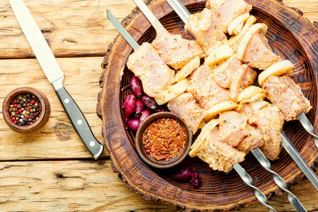 Uncooked raw pork skewers in marinade, on skewers.