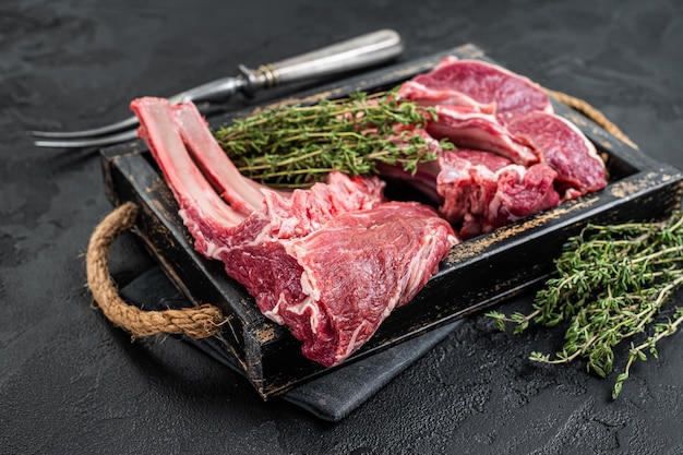 Uncooked Raw Rack and lamb, mutton rib chops  in a wooden tray. Black background. Top view.