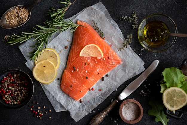 Uncooked raw salmon fish with herbs on dark background