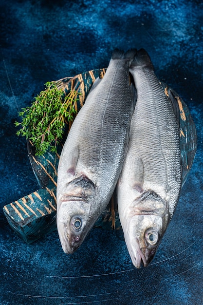 Uncooked Raw Sea Bass fish Seabass with thyme Blue background Top view