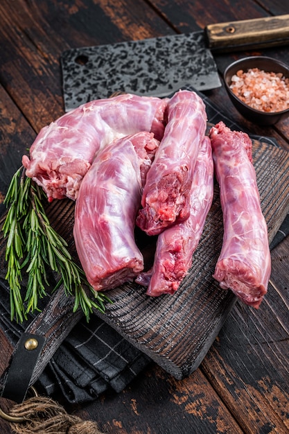 Uncooked raw turkey necks meat on a butcher wooden board with
cleaver. dark wooden background. top view.