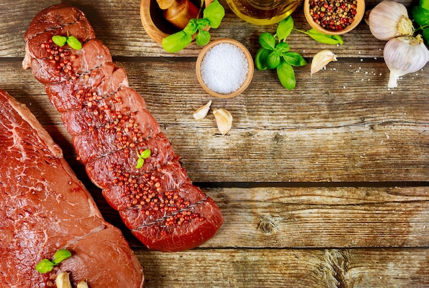 Uncooked red meat on wooden board with spices. Copy space.