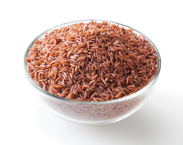 Uncooked red rice in glass bowl isolated on white background with clipping path