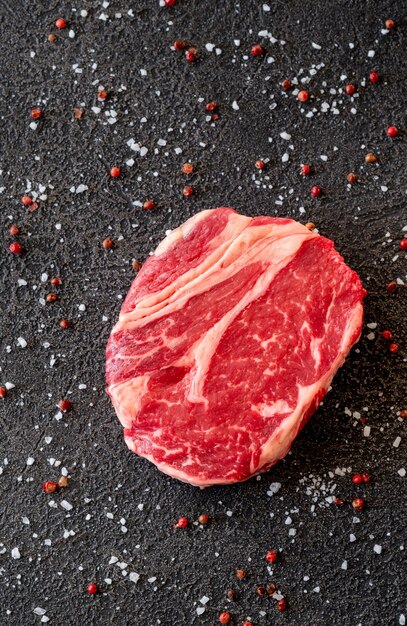 Uncooked rib eye beef steak on the black background