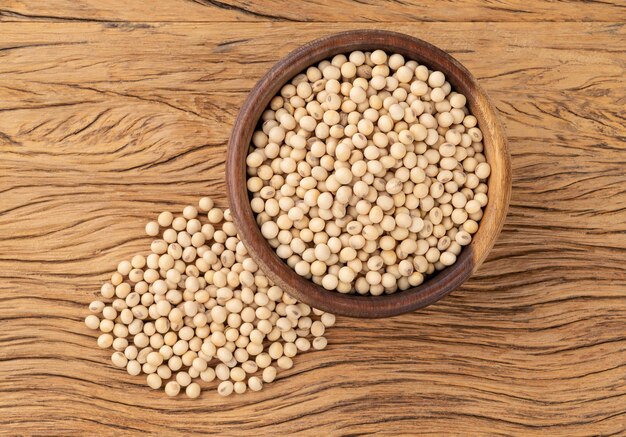 Uncooked soy beans in a bowl over wooden table