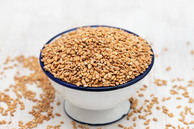 Uncooked spelt in white bowl